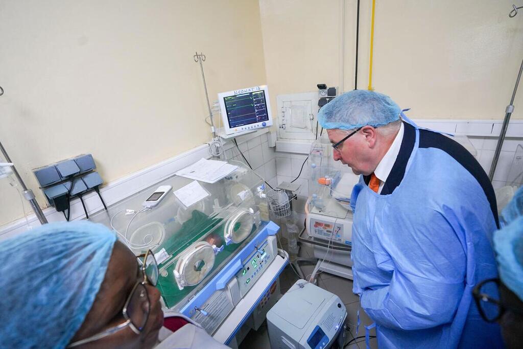 Le directeur exécutif adjoint de l'UNFPA, Andrew Saberton, examine un incubateur dans une maternité tchadienne, vêtu d'une tenue médicale.