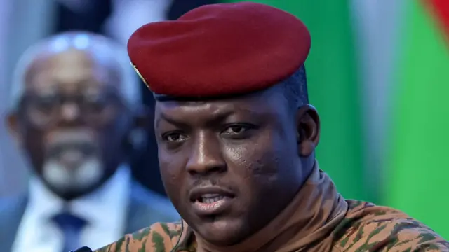 Portrait d'Ibrahim Traoré, vêtu d'une tenue militaire beige et d'un béret rouge, lors d'une interview télévisée.